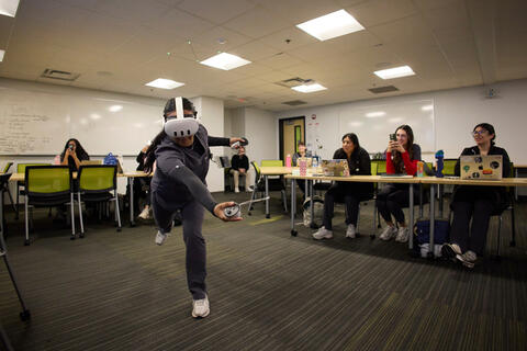 A student reaching out with VR gear on.