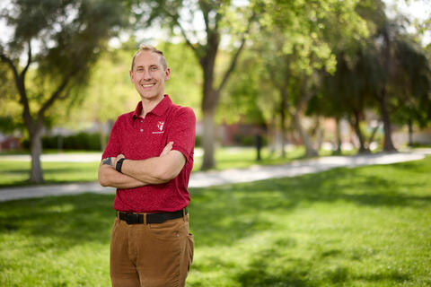 Kenneth Varner in red shirt and arms crossed while standing outside