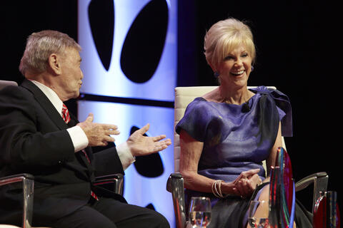 a man and woman in formal attire on a stage