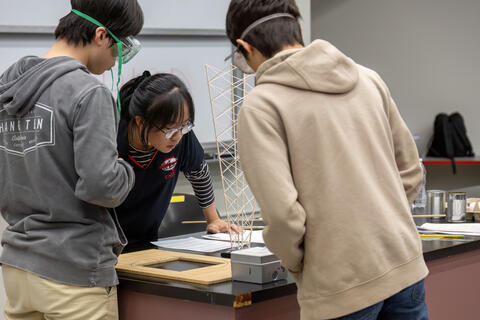 three students work on science experiment