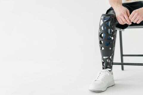 Closeup on the prosthetic right leg of a man sitting on a folding chair