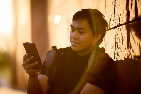 A man staring at his phone while sitting down