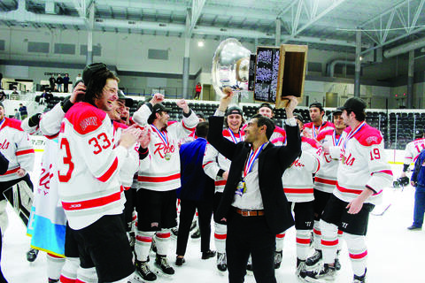 hockey team celebrating as coach holds trophy