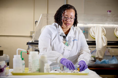 Liuba Williams in a white lab coat and working in a lab