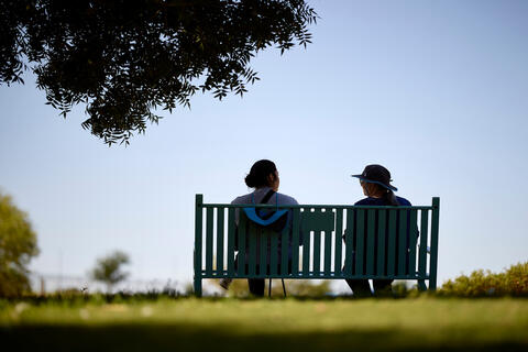 person sits with an elderly patient on bench