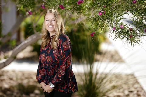 Jennifer Czajkowski in a colorful blouse under a blooming tree on campus