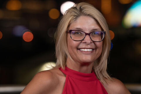woman in red shirt with city lights behind her