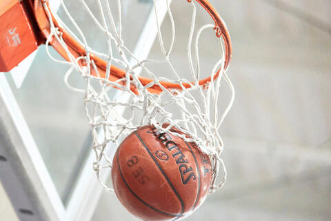 A basketball falling through a hoop.