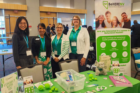 A BeHERE booth with five people behind it