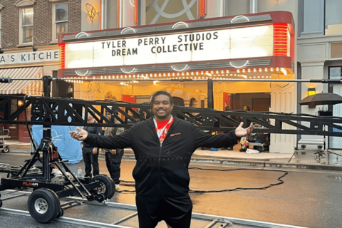 fine arts student stands in front of tyler perry dream arts collective marquee