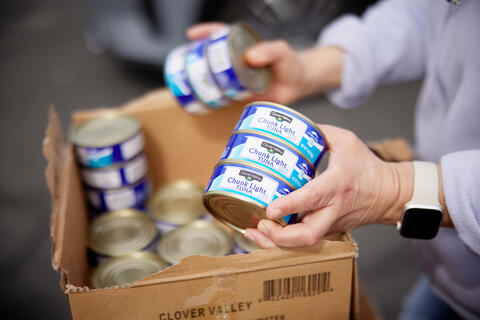 volunteer packing a box with canned tuna