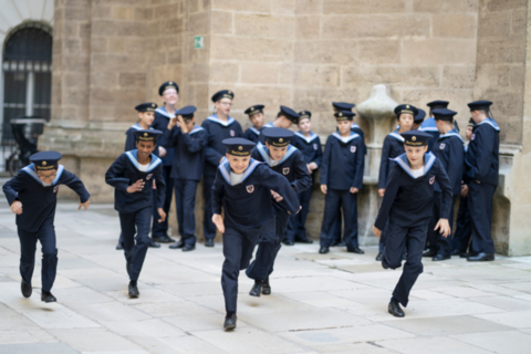 young boys in school uniforms running and standing in a group