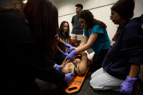 students surround "patient" on stretcher during staged emergency