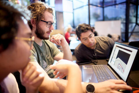 Three students huddled around a computer