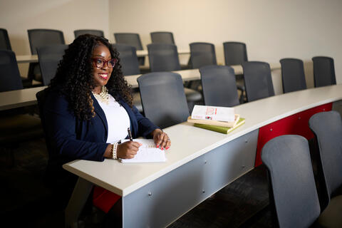 Tiffany Payne in classroom with stack of books and notepad