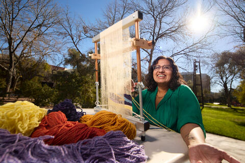 woman working with loom on campus