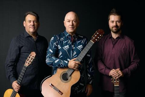three men holding acoustic guitars