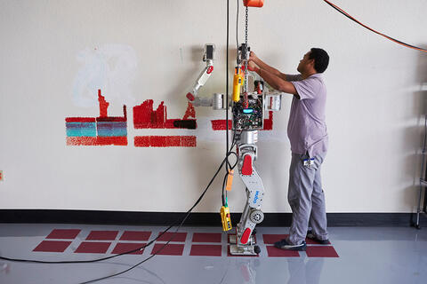 A researcher adjusting a humanoid robot in a lab.