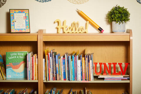 Close up of a bookshelf with children's books and miniature UNLV letters