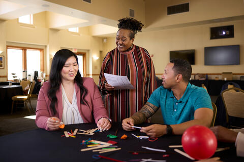 Three people in a table with crafting materials