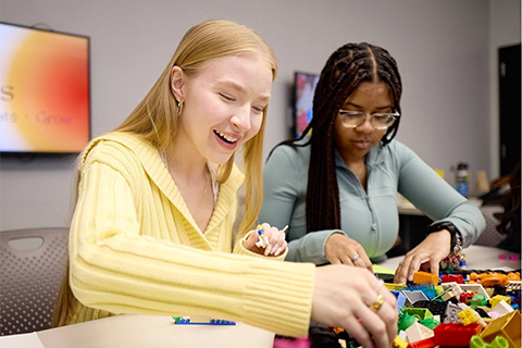 2 students sitting by a table playing with legos
