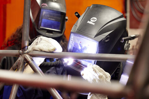 2 students welting metal bars together