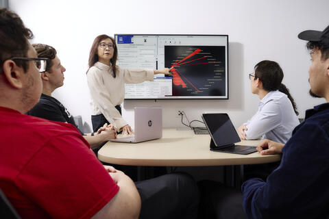 A person pointing to the screen in front of people