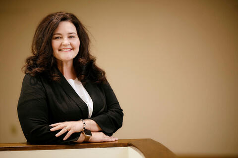 woman in professional clothing posing by a wooden railing