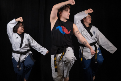 3 people practicing taekwondo in uniforms and black belts with stripes