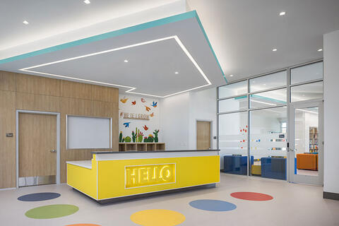 Lobby view of a building with a yellow table and colorful dots on the floor