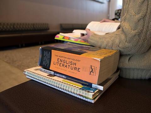 Student reading with a large English Literature textbook next to her notes.