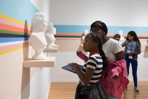 People looking at head statues