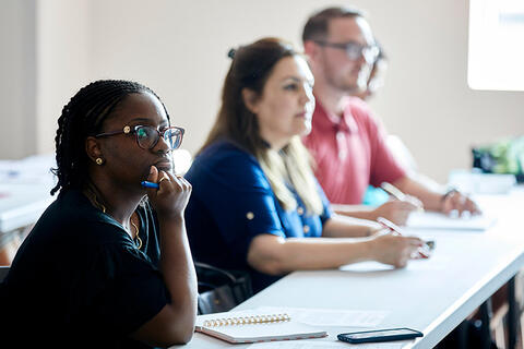 A meeting with faculty members sitting a tables in discussion.