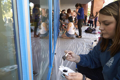 A woman using paint to decorate a window