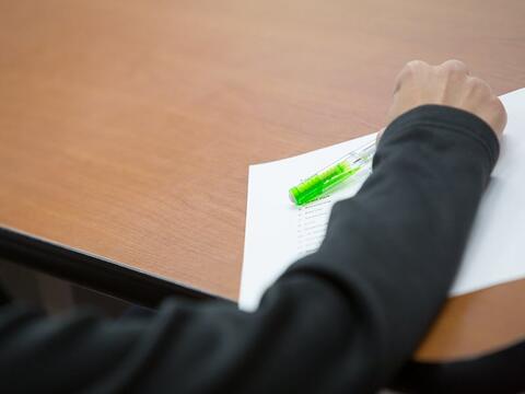 Student writing notes on a sheet of paper.