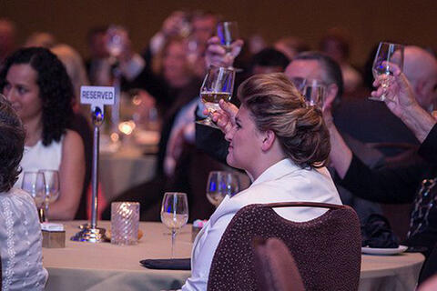 People holding up their drinking glasses at a conference