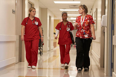 Three nurses walking down a hallway