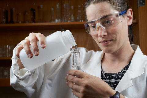Erica Marti fills tube with liquid while wearing protective goggles