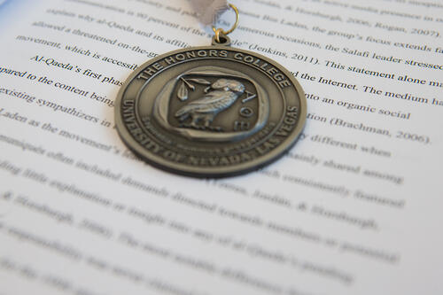 An Honors College medallion laid on top of an open textbook