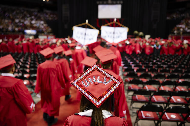 UNLV student at a commencement ceremony. Their cap is bedazzled with the &quot;UNLV&quot; in the center.