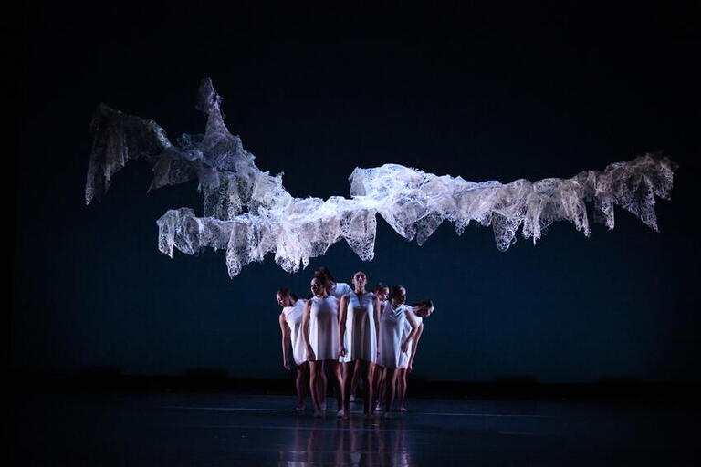 Group of dancers huddled together on a dark stage