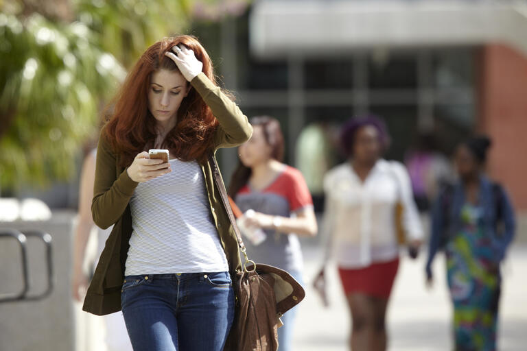 woman walking and looking at cell phone