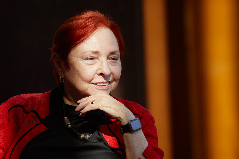 A woman with red hair rests her hadn on her chin