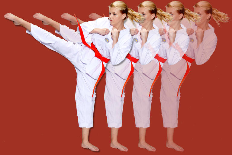 A woman in a karate gi kicks.