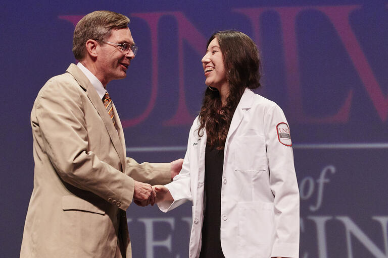 man shaking hand of woman in doctor's coat