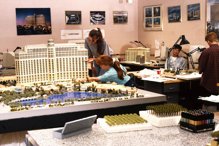 Two workers lean in to work on a model of the Bellagio.