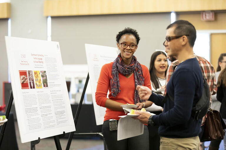 Woman talking to man in front of academic research poster