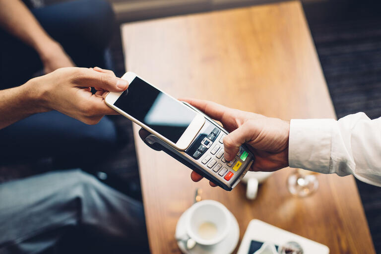 A smartphone is used to enact a contactless payment at a restaurant
