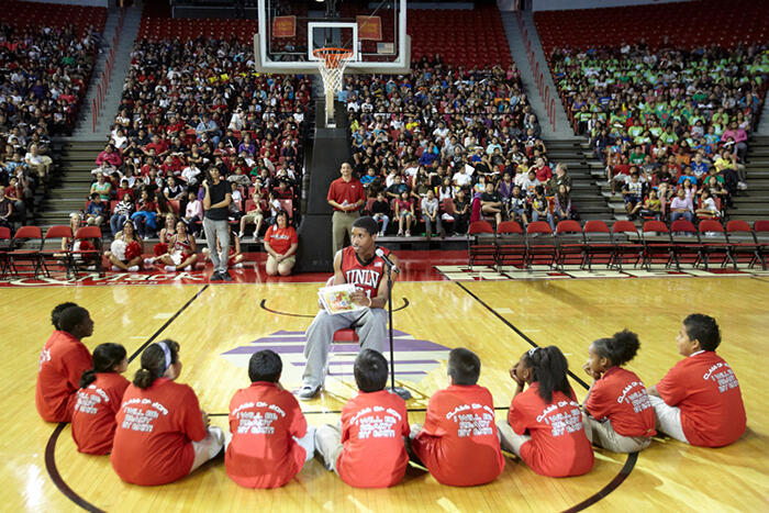 Justin Hawkins, a guard on UNLV's basketball team, reads to students on the basketball court.