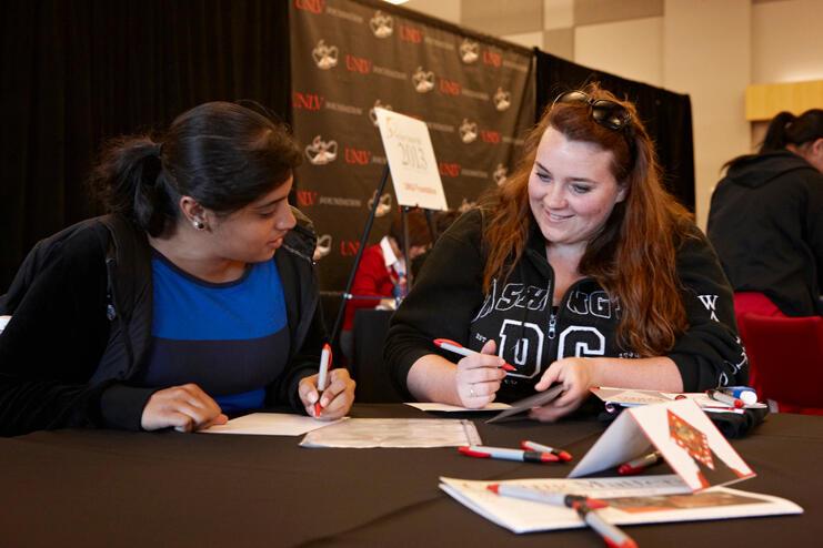Two students writing notes on paper.